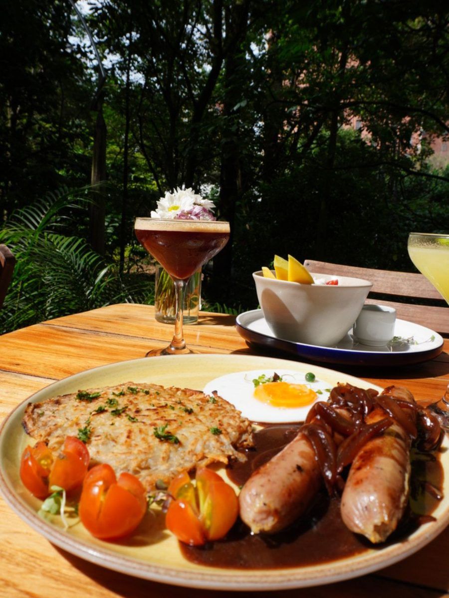 Bratwurst with rösti at Bread Factory: two sausages in onion sauce, a fried egg and cherry tomatoes, served in the garden