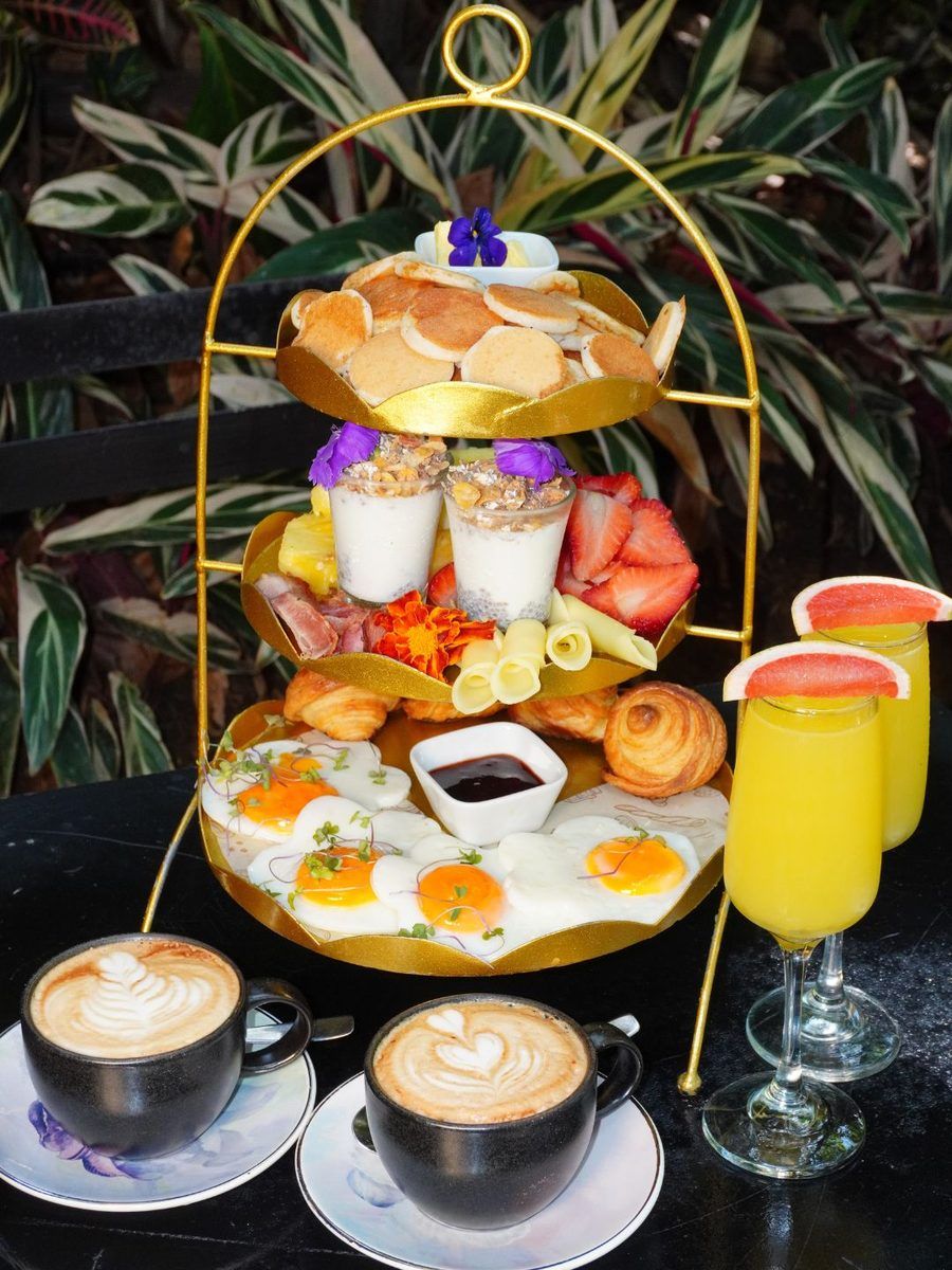 The Znüni, Bread Factory’s brunch for two, on a gold stand: fried eggs, mini pancakes, mini croissants, parfaits, ham, cheese and fruit, with two cappuccinos and two mimosas